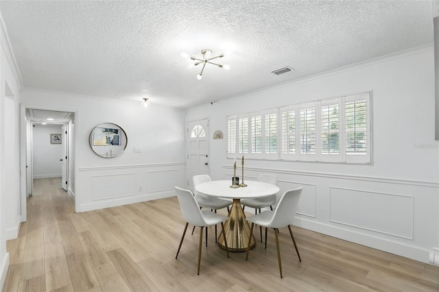 4611 Cranston Pl, Orlando, FL 32812 - dining area with crown molding, a decorative wall, a textured ceiling, and light wood-style floors