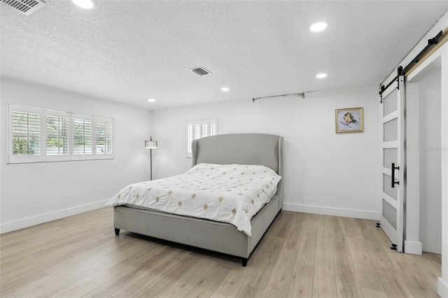 4611 Cranston Pl, Orlando, FL 32812 - bedroom with a barn door, a textured ceiling, recessed lighting, and light wood finished floors
