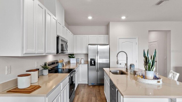 2016 Monteverde Ave, Davenport, FL 33837 - kitchen featuring stainless steel appliances, wood finished floors, white cabinets, an island with sink, and recessed lighting