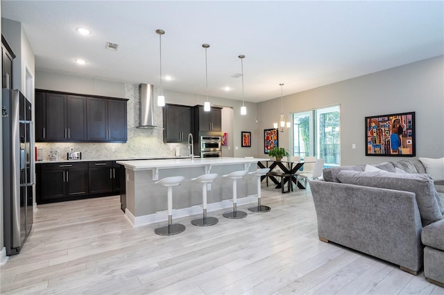 8066 Ludington Cir, Orlando, FL 32836 - kitchen featuring wall chimney range hood, open floor plan, high end fridge, a breakfast bar area, and light wood-type flooring