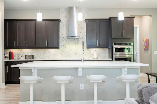 8066 Ludington Cir, Orlando, FL 32836 - kitchen with wall chimney exhaust hood, double oven, a breakfast bar area, and tasteful backsplash