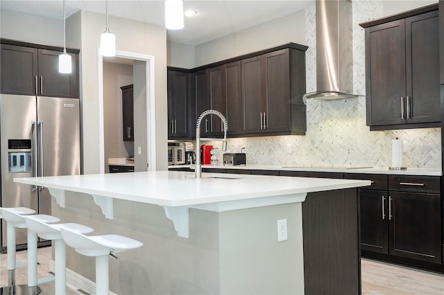 8066 Ludington Cir, Orlando, FL 32836 - kitchen featuring high quality fridge, wall chimney exhaust hood, a kitchen island with sink, decorative backsplash, and a breakfast bar area
