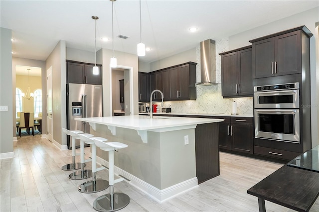 8066 Ludington Cir, Orlando, FL 32836 - kitchen with wall chimney range hood, appliances with stainless steel finishes, light wood-style floors, dark brown cabinets, and recessed lighting