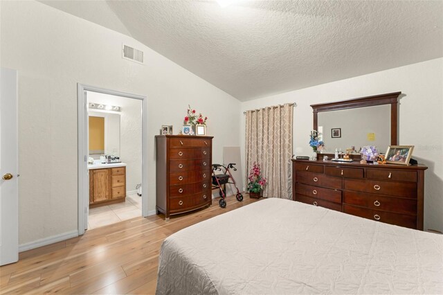 470 Cardinal Ct, Kissimmee, FL 34759 - bedroom featuring vaulted ceiling, light wood-style flooring, a textured ceiling, and connected bathroom