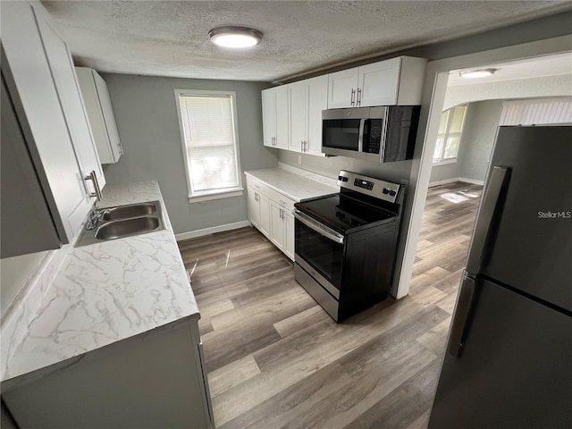 2107 Hollywood Ave, Eustis, FL 32726 - kitchen featuring stainless steel appliances, a textured ceiling, light countertops, white cabinetry, and wood finished floors