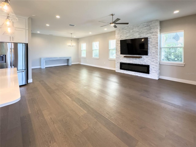 16210 Ravenna Ct, Montverde, FL 34756 - unfurnished living room featuring a chandelier, a stone fireplace, ceiling fan, dark wood-type flooring, and recessed lighting