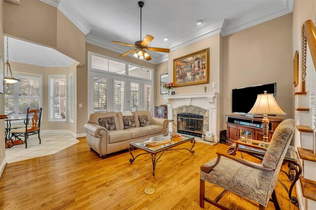 413 Harbour Oaks Pointe Dr, Edgewood, FL 32809 - living room featuring a ceiling fan, a glass covered fireplace, crown molding, wood finished floors, and healthy amount of natural light