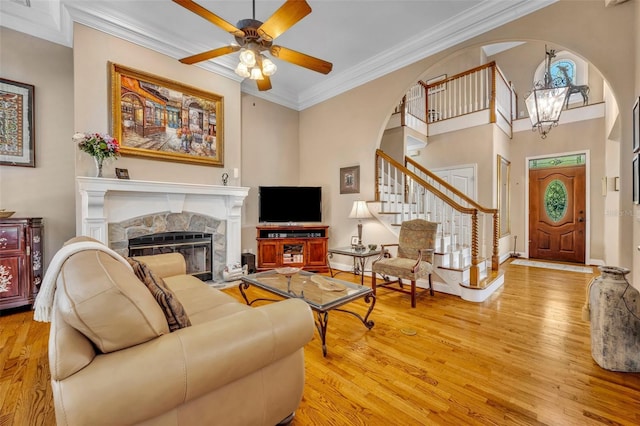 413 Harbour Oaks Pointe Dr, Edgewood, FL 32809 - living area featuring arched walkways, a stone fireplace, crown molding, and light wood-style floors