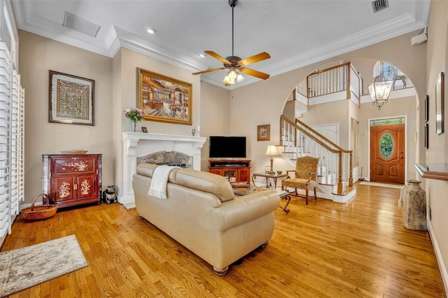 413 Harbour Oaks Pointe Dr, Edgewood, FL 32809 - living area with arched walkways, light wood-type flooring, ornamental molding, a ceiling fan, and a fireplace