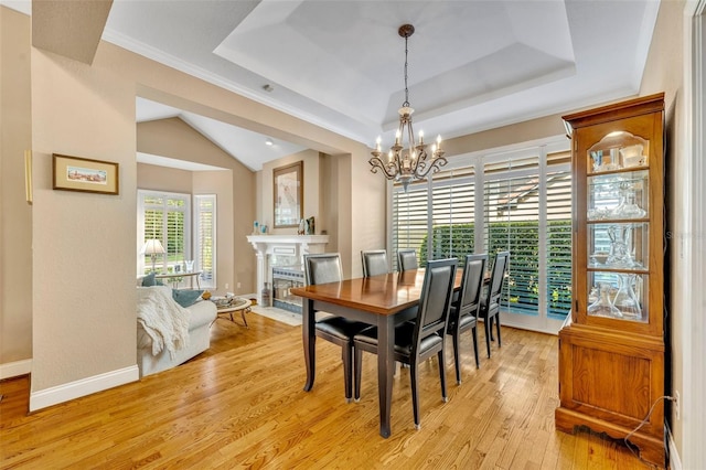 413 Harbour Oaks Pointe Dr, Edgewood, FL 32809 - dining area with a chandelier, a tray ceiling, light wood-style flooring, a fireplace, and ornamental molding