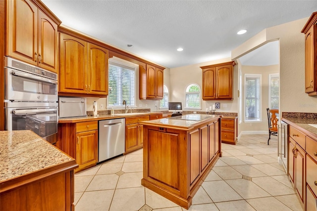413 Harbour Oaks Pointe Dr, Edgewood, FL 32809 - kitchen with appliances with stainless steel finishes, a center island, brown cabinets, light tile patterned flooring, and recessed lighting