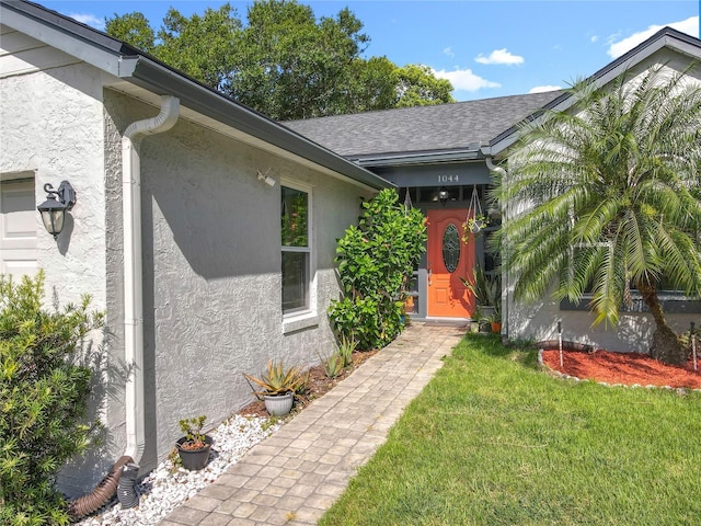 1044 Dees Dr, Oviedo, FL 32765 - entrance to property featuring stucco siding, a lawn, and a shingled roof
