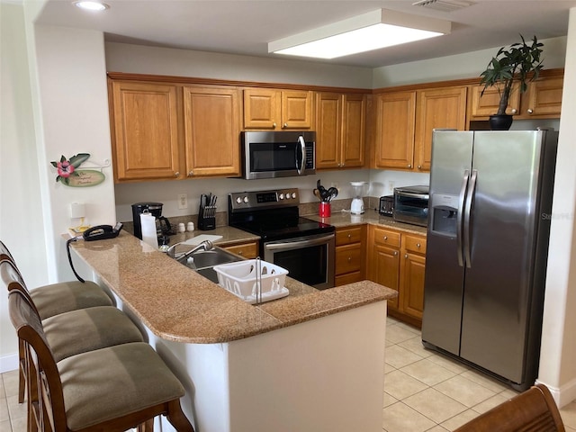 13415 Blue Heron Bch Unit 203, Orlando, FL 32821 - kitchen with appliances with stainless steel finishes, a peninsula, brown cabinetry, light tile patterned flooring, and recessed lighting