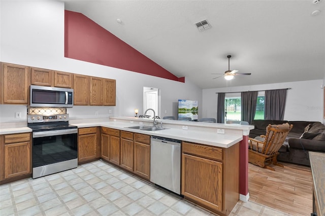 1113 Canopy Oaks Dr, Minneola, FL 34715 - kitchen with appliances with stainless steel finishes, open floor plan, a peninsula, brown cabinets, and light countertops