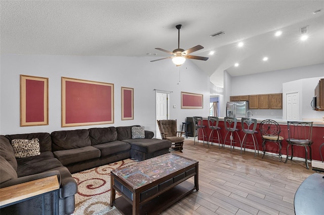 1113 Canopy Oaks Dr, Minneola, FL 34715 - living room featuring a ceiling fan, light wood-style flooring, high vaulted ceiling, and a textured ceiling