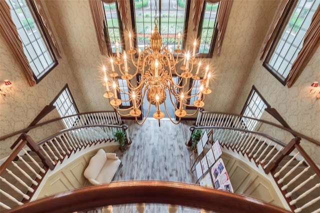 25105 Laurel Valley Rd, Leesburg, FL 34748 - stairs with a towering ceiling, a chandelier, wallpapered walls, and wood finished floors