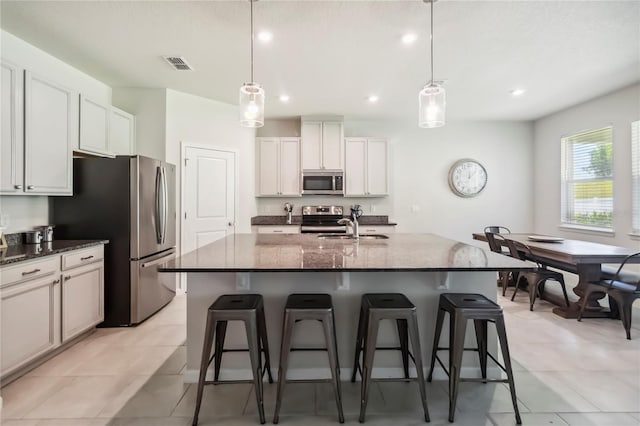 3142 Hill Point St, Minneola, FL 34715 - kitchen featuring stainless steel appliances, a breakfast bar, dark stone countertops, a kitchen island with sink, and pendant lighting