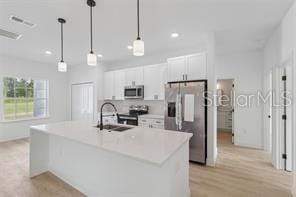 4572 SW 149th St, Ocala, FL 34473 - kitchen with stainless steel appliances, white cabinetry, a center island with sink, recessed lighting, and pendant lighting