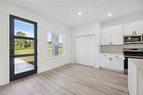 4572 SW 149th St, Ocala, FL 34473 - kitchen featuring stainless steel microwave, electric range, light wood finished floors, white cabinets, and light countertops