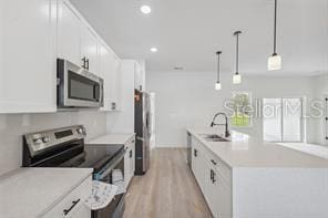 4572 SW 149th St, Ocala, FL 34473 - kitchen with stainless steel appliances, a kitchen island with sink, white cabinetry, light wood-type flooring, and light countertops