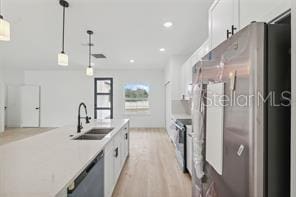 4572 SW 149th St, Ocala, FL 34473 - kitchen with stainless steel appliances, white cabinets, light wood-style floors, decorative light fixtures, and recessed lighting