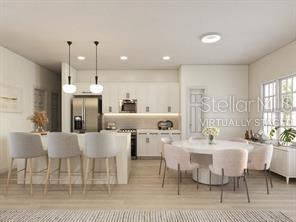 4572 SW 149th St, Ocala, FL 34473 - kitchen with stainless steel fridge, a kitchen breakfast bar, recessed lighting, decorative light fixtures, and white cabinetry