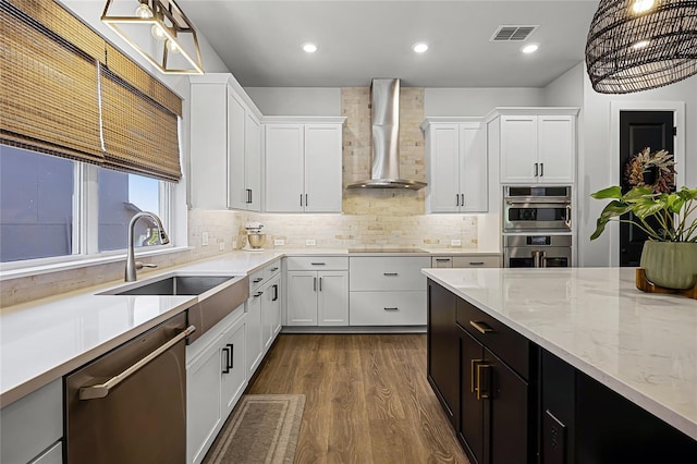 17290 Hickory Wind Dr, Clermont, FL 34711 - kitchen with appliances with stainless steel finishes, wall chimney range hood, dark wood-type flooring, white cabinetry, and backsplash