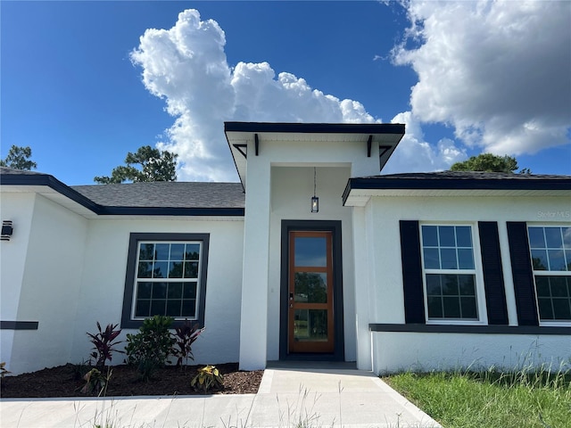 569 Marion Oaks Mnr, Ocala, FL 34473 - view of exterior entry with stucco siding and a shingled roof