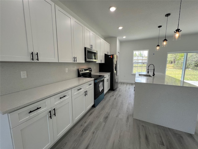 569 Marion Oaks Mnr, Ocala, FL 34473 - kitchen featuring appliances with stainless steel finishes, light wood finished floors, white cabinetry, recessed lighting, and hanging light fixtures