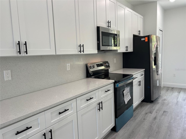 569 Marion Oaks Mnr, Ocala, FL 34473 - kitchen featuring stainless steel appliances, white cabinetry, light wood-type flooring, decorative backsplash, and light stone countertops