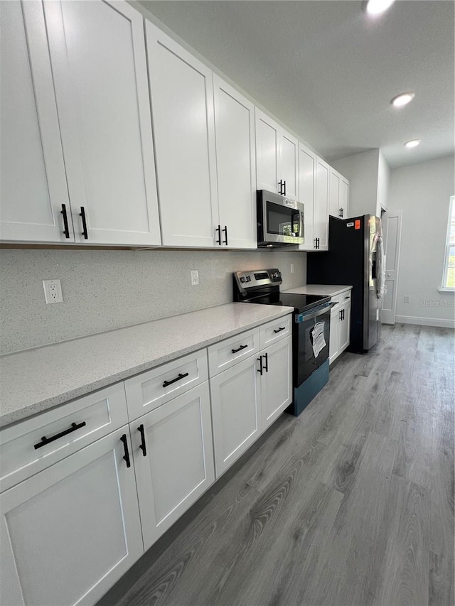 569 Marion Oaks Mnr, Ocala, FL 34473 - kitchen with appliances with stainless steel finishes, light wood-type flooring, white cabinetry, recessed lighting, and light stone countertops