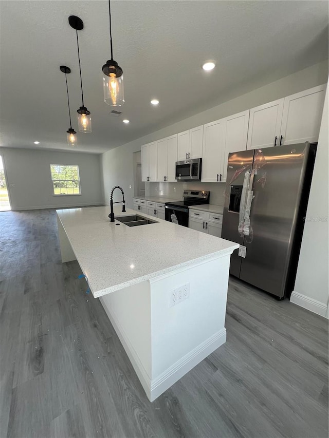 569 Marion Oaks Mnr, Ocala, FL 34473 - kitchen featuring stainless steel appliances, wood finished floors, white cabinets, a large island, and pendant lighting
