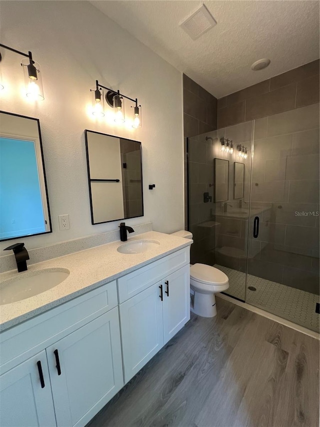 569 Marion Oaks Mnr, Ocala, FL 34473 - bathroom with wood finished floors, a textured ceiling, a shower stall, and double vanity