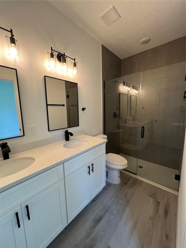 569 Marion Oaks Mnr, Ocala, FL 34473 - bathroom featuring wood finished floors, a textured ceiling, a shower stall, and double vanity