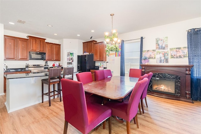 30308 Cheval St, Mount Dora, FL 32757 - dining room featuring light wood finished floors, a chandelier, recessed lighting, and a premium fireplace