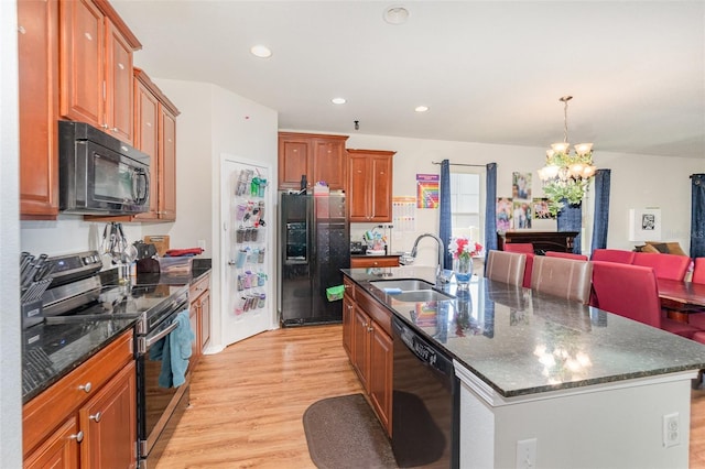 30308 Cheval St, Mount Dora, FL 32757 - kitchen with black appliances, a chandelier, light wood finished floors, an island with sink, and brown cabinets