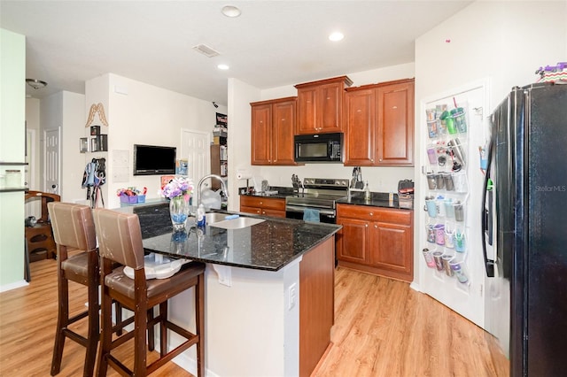 30308 Cheval St, Mount Dora, FL 32757 - kitchen with black appliances, light wood-type flooring, an island with sink, a kitchen bar, and recessed lighting