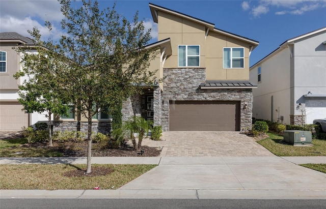 1811 Caribbean View Ter, Kissimmee, FL 34747 - view of front of home featuring stone siding, an attached garage, decorative driveway, a standing seam roof, and stucco siding