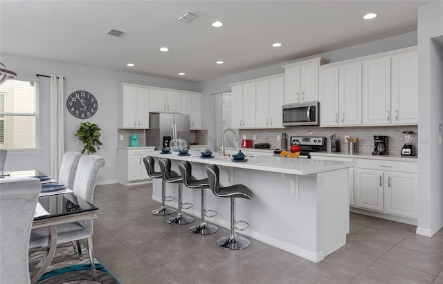 1811 Caribbean View Ter, Kissimmee, FL 34747 - kitchen featuring stainless steel appliances, backsplash, an island with sink, white cabinets, and recessed lighting
