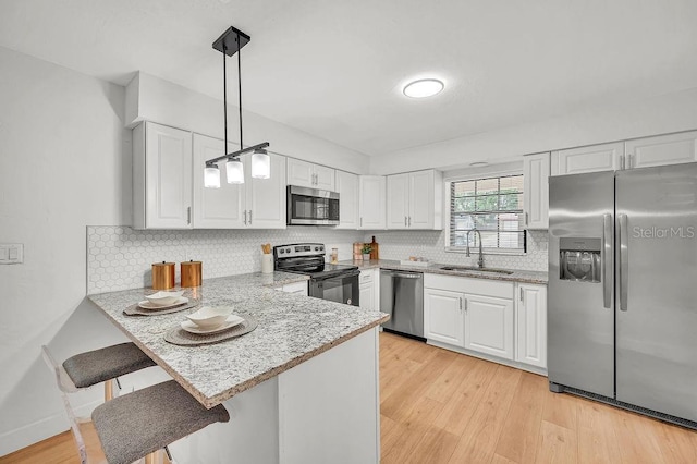5460 SE 28th St, Ocala, FL 34480 - kitchen featuring stainless steel appliances, white cabinets, a peninsula, a breakfast bar, and pendant lighting