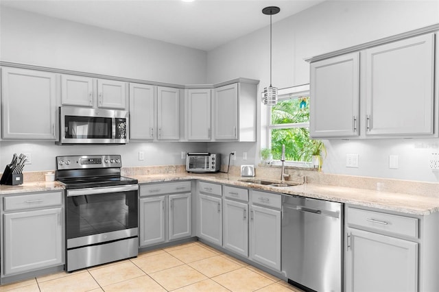 1785 Rushden Dr, Ocoee, FL 34761 - kitchen with appliances with stainless steel finishes, gray cabinetry, light tile patterned floors, hanging light fixtures, and light stone countertops