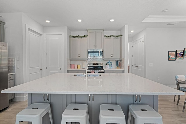 1388 Lombardi Ct, Kissimmee, FL 34759 - kitchen with stainless steel appliances, light wood-style floors, a kitchen bar, and recessed lighting