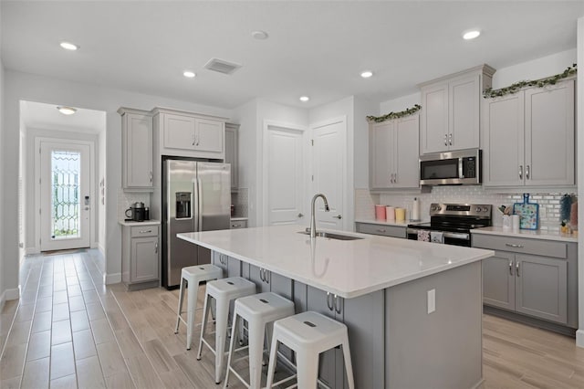 1388 Lombardi Ct, Kissimmee, FL 34759 - kitchen with stainless steel appliances, gray cabinetry, decorative backsplash, a kitchen breakfast bar, and a center island with sink