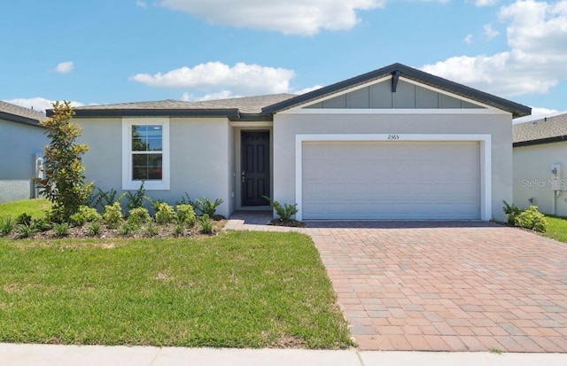 2365 White Tail St, Davenport, FL 33837 - ranch-style house with decorative driveway, a front yard, an attached garage, and stucco siding
