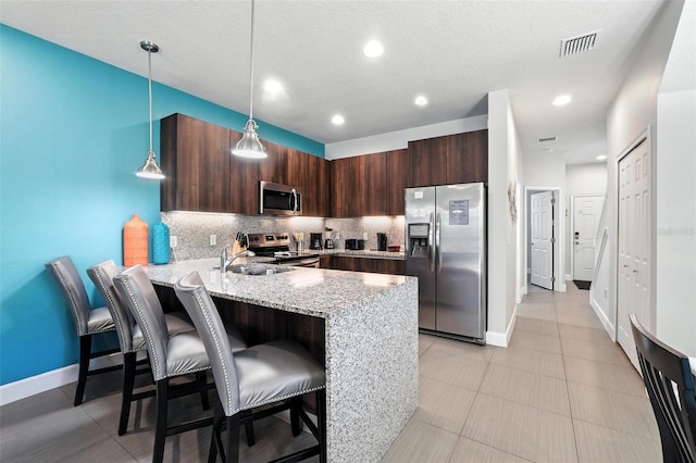 1530 Retreat Cir, Clermont, FL 34714 - kitchen featuring stainless steel appliances, a peninsula, backsplash, a kitchen breakfast bar, and dark brown cabinets