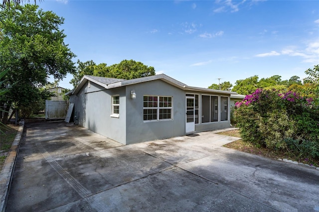 540 W Columbia St, Lake Alfred, FL 33850 - rear view of property featuring stucco siding, concrete driveway, a patio area, and a sunroom