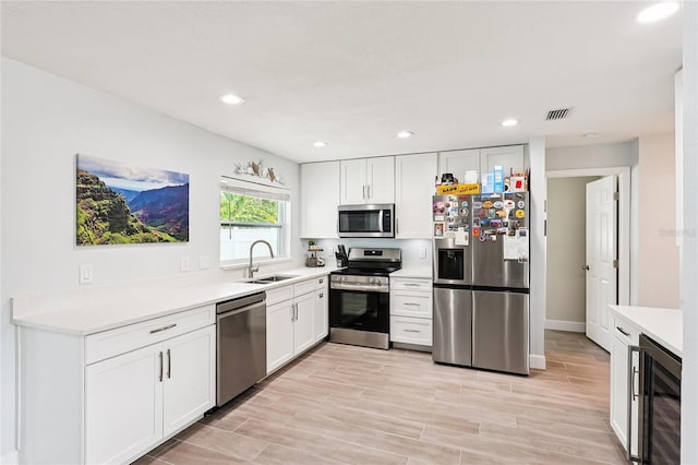 2926 Carriage Dr, South Daytona, FL 32119 - kitchen featuring appliances with stainless steel finishes, beverage cooler, white cabinets, light countertops, and recessed lighting