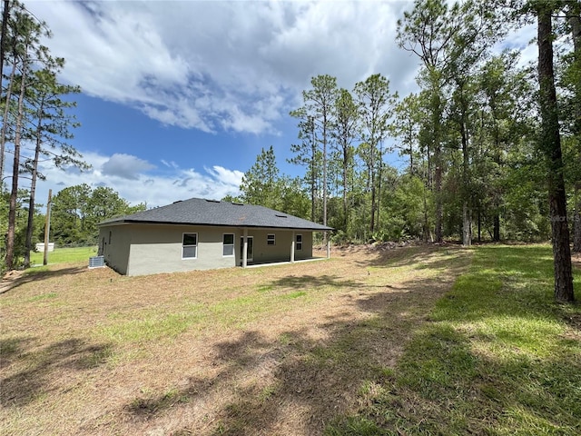 7687 N Quibble Ave, Dunnellon, FL 34434 - rear view of property with stucco siding and a yard