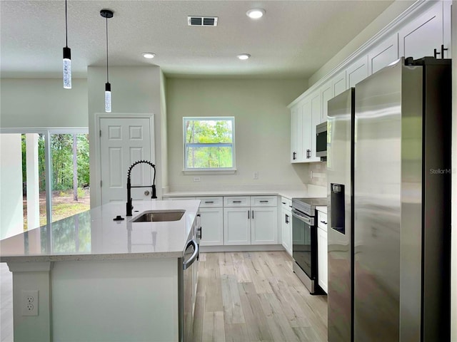 8051 N Pinkinz Way, Citrus Springs, FL 34433 - kitchen with stainless steel appliances, light wood finished floors, white cabinets, a kitchen island with sink, and recessed lighting