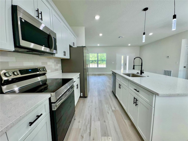8051 N Pinkinz Way, Citrus Springs, FL 34433 - kitchen featuring appliances with stainless steel finishes, light wood-style floors, recessed lighting, white cabinets, and a center island with sink